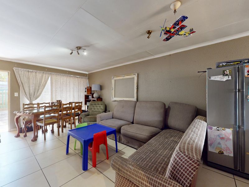 Open-plan living and dining area featuring tiled flooring and access to an outdoor patio through a sliding glass door.