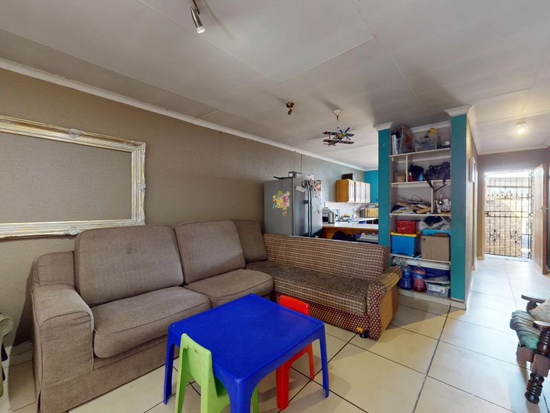 Open plan living area featuring tiled flooring and a built-in shelving unit, connecting to the kitchen space.