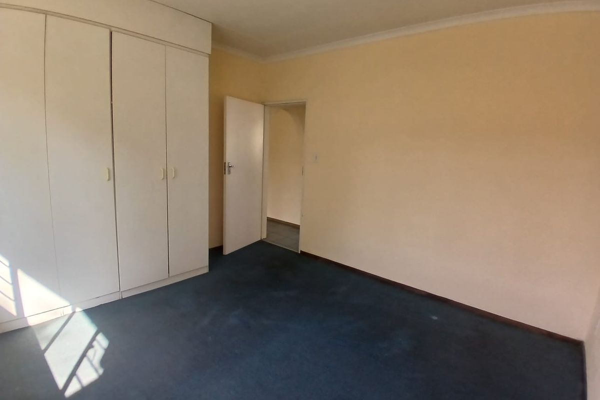 An empty bedroom featuring built-in cupboards, carpeted flooring, and coved ceilings, offering a blank canvas for potential updates.