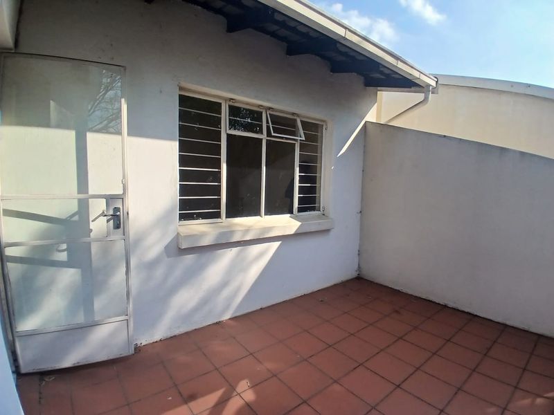 A private outdoor patio area featuring tiled flooring, security gate access, and window security bars, offering a functional space for outdoor relaxation.