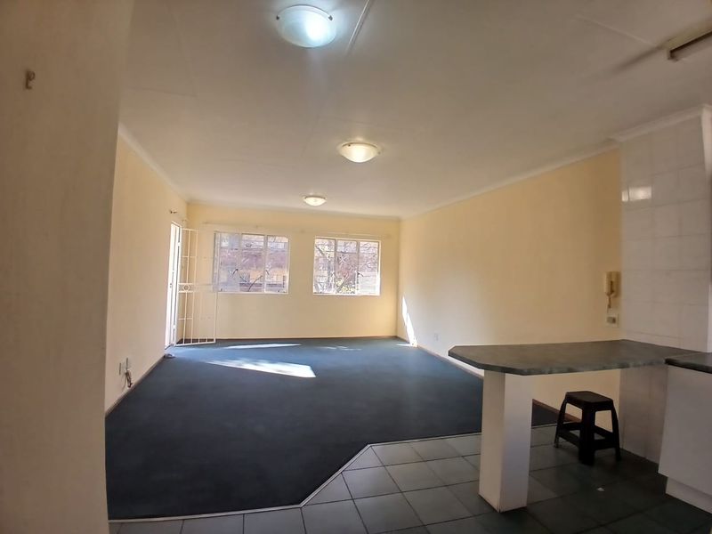 Spacious open-plan living area featuring a breakfast bar, tiled kitchen transition, and carpeted lounge space with natural light.