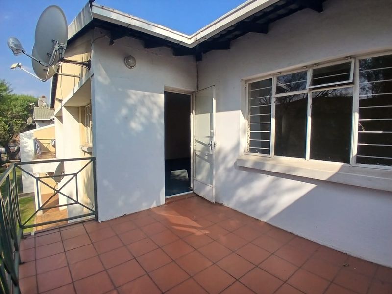 An elevated balcony area featuring tiled flooring, metal balustrades, and security bars on the windows, providing an outdoor space accessible from the interior.