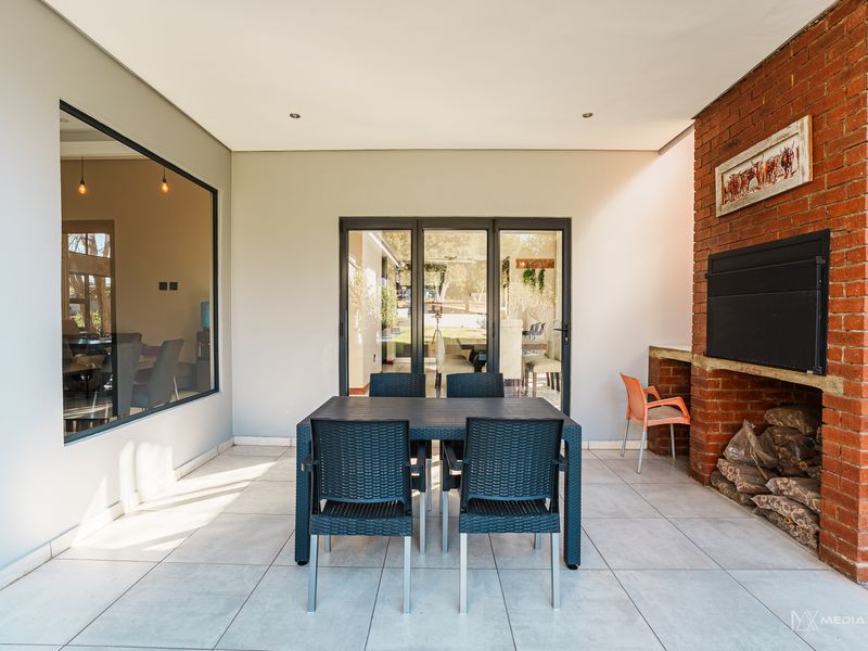 Covered patio area featuring a built-in brick braai, tiled flooring, and large aluminium sliding doors providing seamless access to the interior living space.