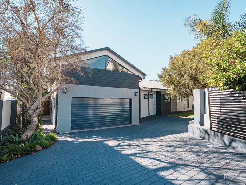 Modern front elevation featuring a paved driveway, automated garage, and distinctive gabled architectural detailing.