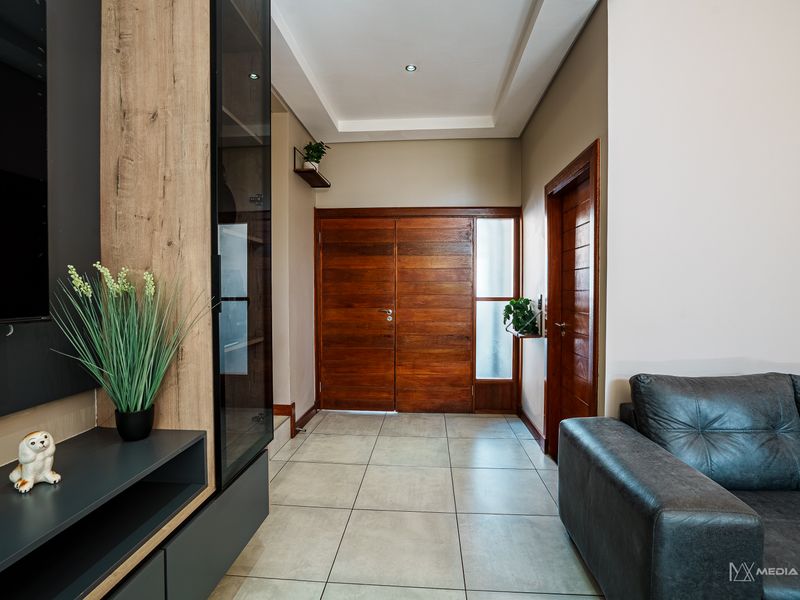 Modern entrance hall featuring tiled flooring, recessed ceiling with downlights, and a solid timber double front door.
