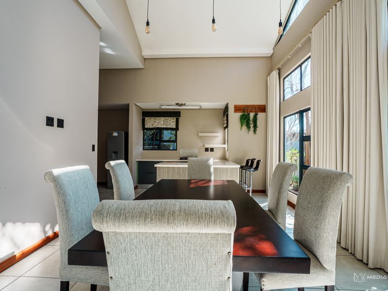 Spacious open-plan living and dining area featuring a vaulted ceiling, large windows for natural light, and a modern kitchen with a central island.