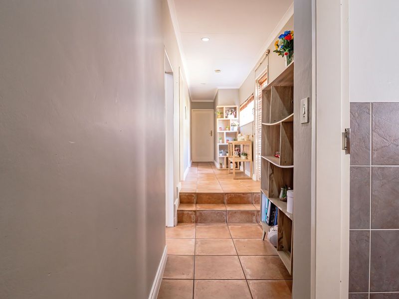 A tiled hallway featuring a step transition leading to further living areas, illuminated by recessed downlights.