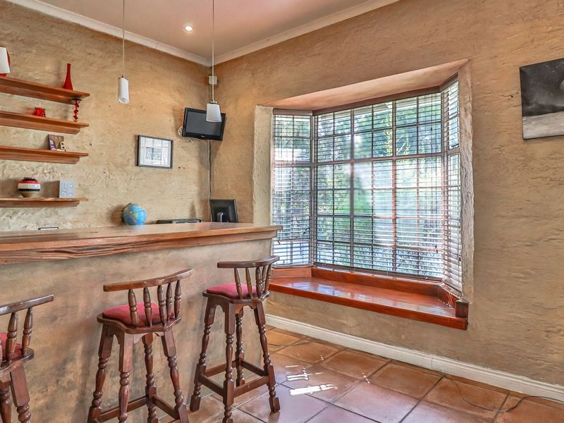 A rustic-style home bar featuring a built-in counter, tiled flooring, and a charming bay window with a built-in window seat.