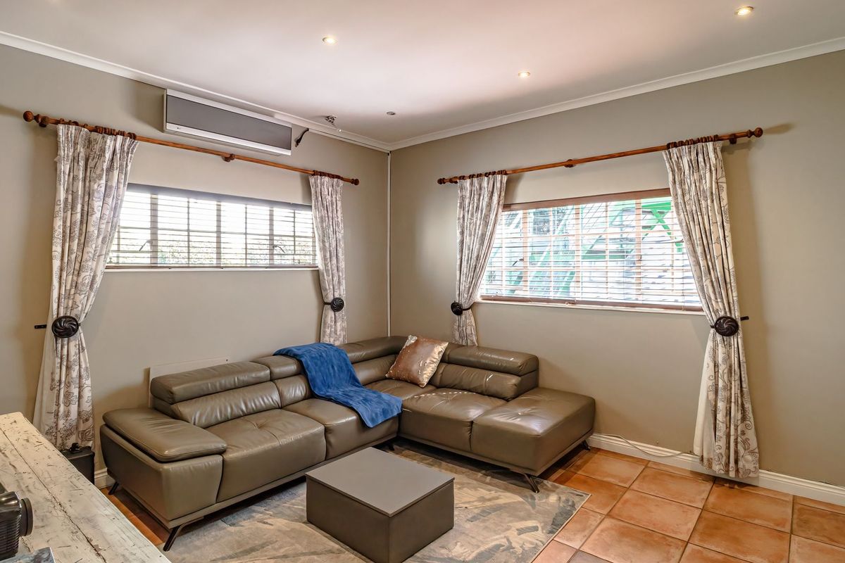 A comfortable living room featuring tiled flooring, recessed downlighting, and a wall-mounted air conditioning unit, providing a functional and well-maintained space.