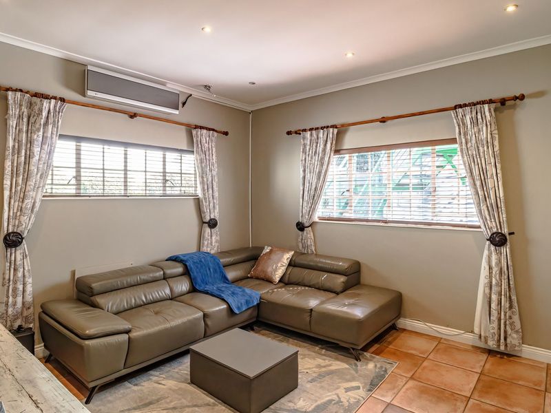 A comfortable living room featuring tiled flooring, recessed downlighting, and a wall-mounted air conditioning unit, providing a functional and well-maintained space.