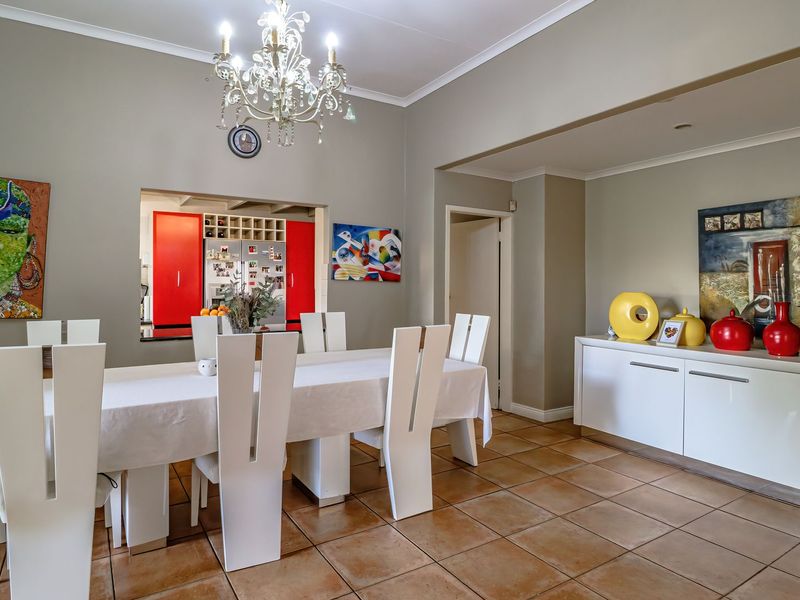 Spacious dining room featuring ceramic tile flooring, decorative cornice, and a convenient pass-through window connecting to the kitchen area.