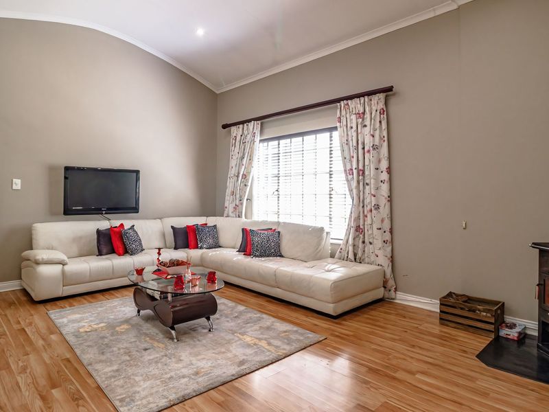 Spacious living room featuring a vaulted ceiling, laminate flooring, and a cozy freestanding wood-burning fireplace.