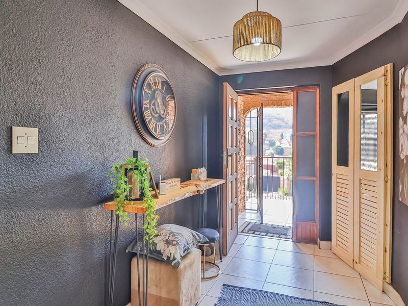 A welcoming entrance hall featuring tiled flooring, dark accent walls, and timber louvered doors, leading directly to an outdoor balcony area.