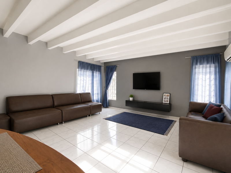 A spacious living room featuring white exposed beam ceilings, neutral grey walls, tiled flooring, and a wall-mounted floating media console.
