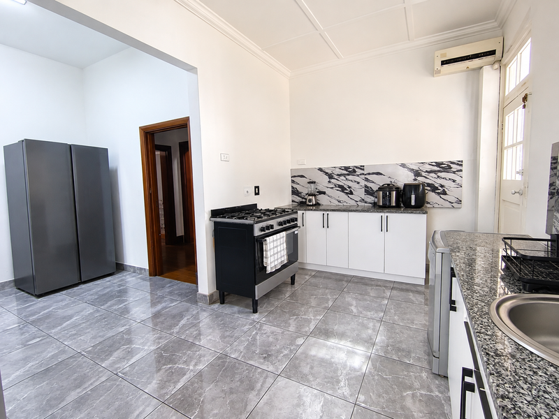 Modern kitchen featuring marble-look backsplash, granite countertops, gas stove, and tiled flooring, offering a clean and functional cooking space.