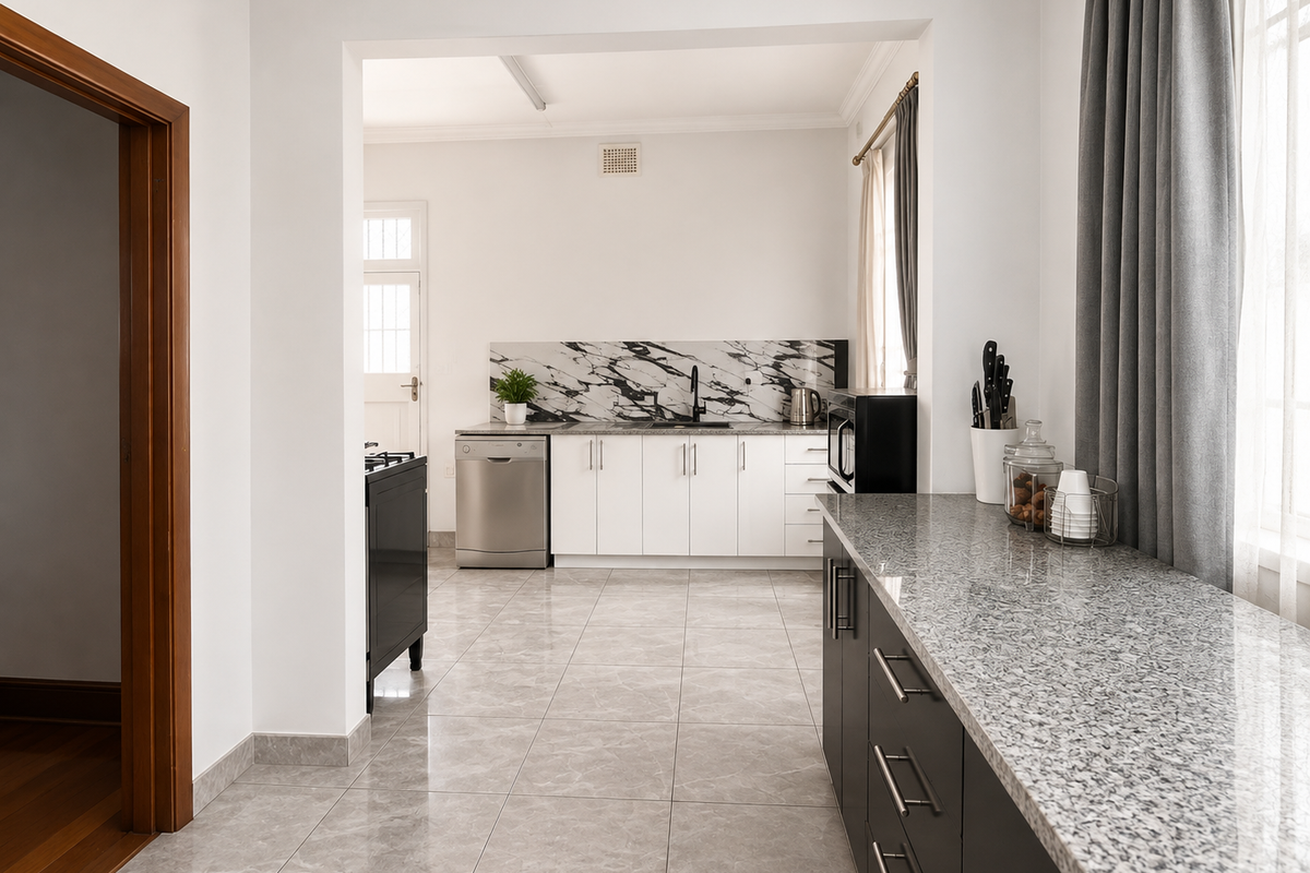 A modern kitchen featuring white cabinetry, marble-look splashback, granite countertops, and tiled flooring, offering a clean and functional workspace.