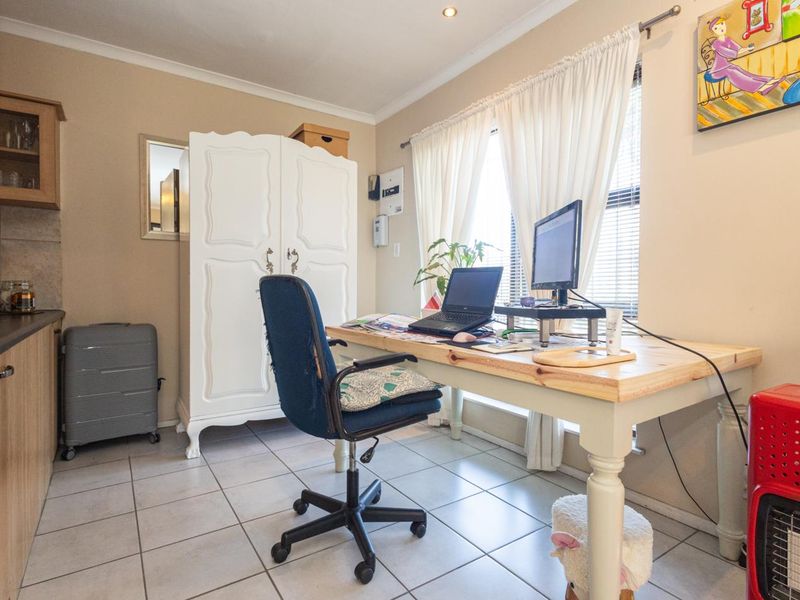 A functional home office space featuring tiled flooring, built-in cabinetry, and natural light from the window.