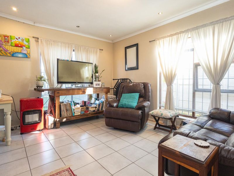 A bright living room featuring tiled flooring, recessed downlighting, and large windows with curtain treatments, offering a functional and well-lit living space.