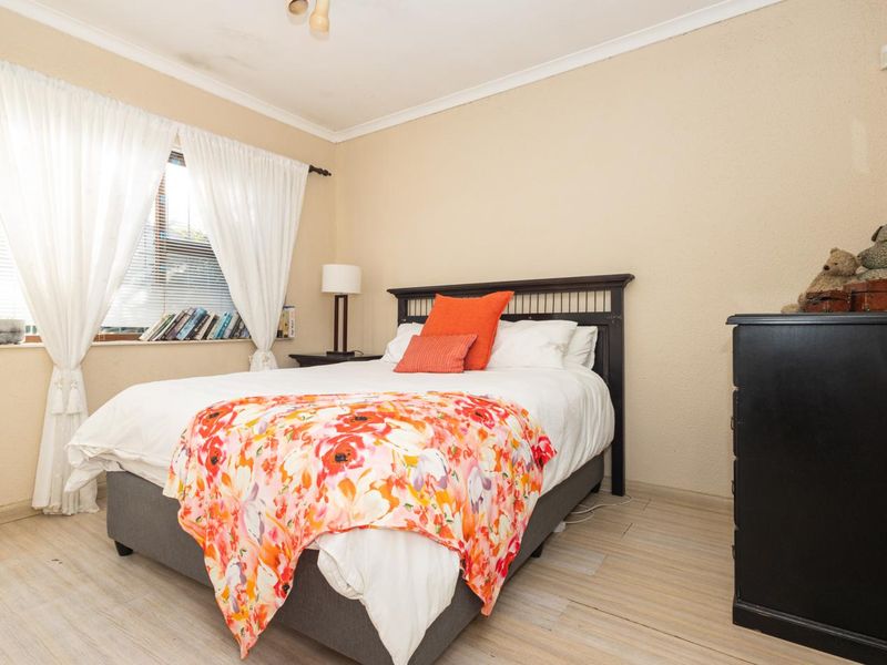 A standard bedroom featuring tiled flooring, coved ceilings, and a window with natural light.