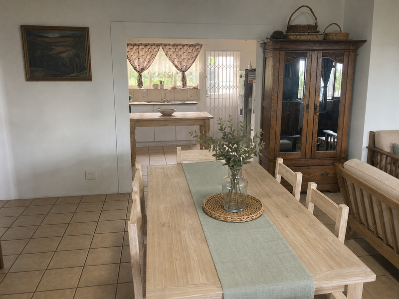 Open plan dining area leading into a functional kitchen with tiled flooring and neutral finishes.