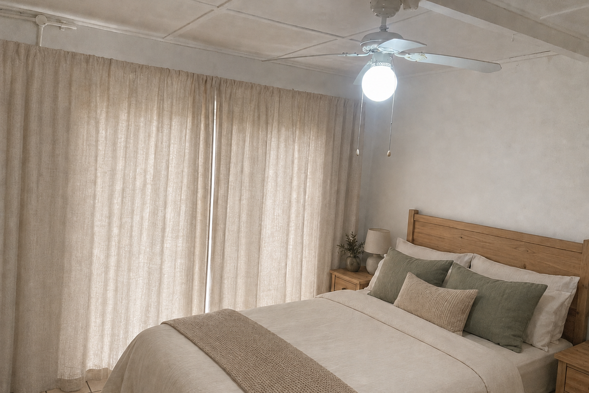 A bedroom featuring tiled flooring, a ceiling fan, and large window curtains, providing a functional space with potential for aesthetic updates.