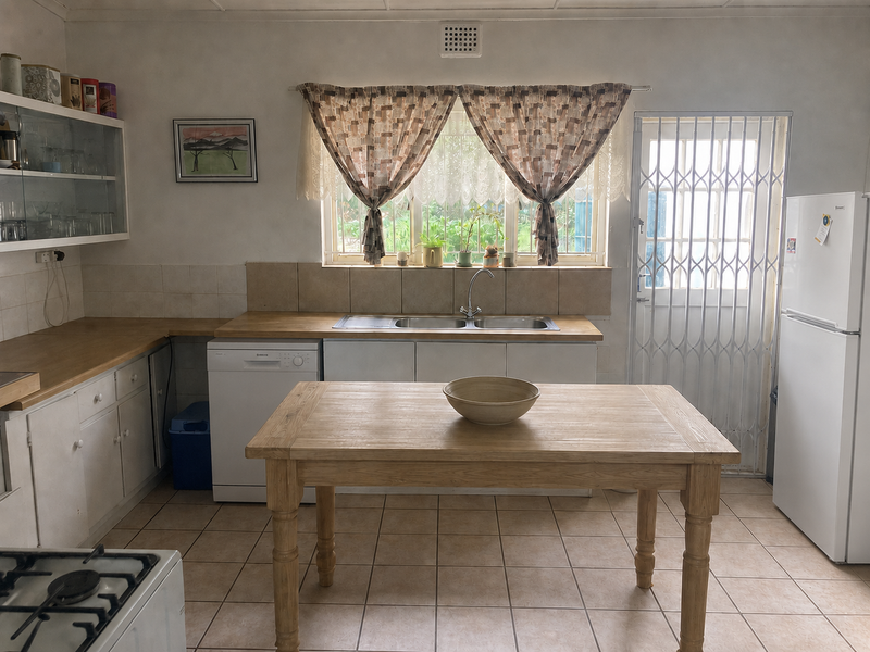 A functional kitchen featuring tiled flooring, built-in cabinetry, a double bowl sink, and a security gate leading to the exterior.