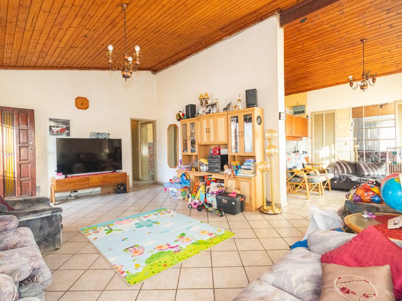 Spacious open-plan living area featuring a high timber-clad vaulted ceiling, ceramic tiled flooring, and integrated cabinetry, offering a versatile layout for family living.