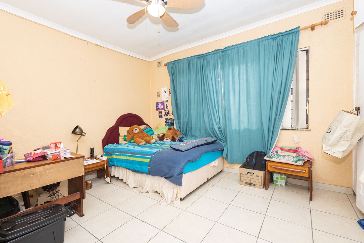 A bedroom featuring tiled flooring, a ceiling fan, and security burglar bars on the window.
