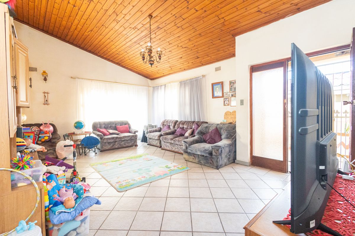 Spacious living room featuring a high timber-clad vaulted ceiling, ceramic tiled flooring, and direct access to the exterior through a glass-panelled door.
