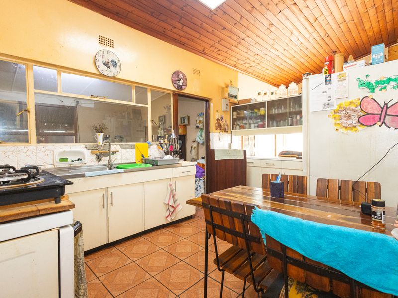 A dated kitchen featuring timber ceilings, tiled flooring, and built-in cabinetry, offering significant potential for a modern renovation.