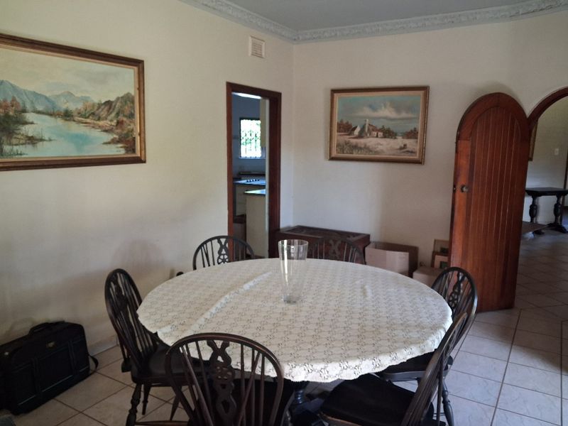 A dining room featuring tiled flooring, decorative ceiling cornicing, and an arched wooden door leading to adjacent living spaces.