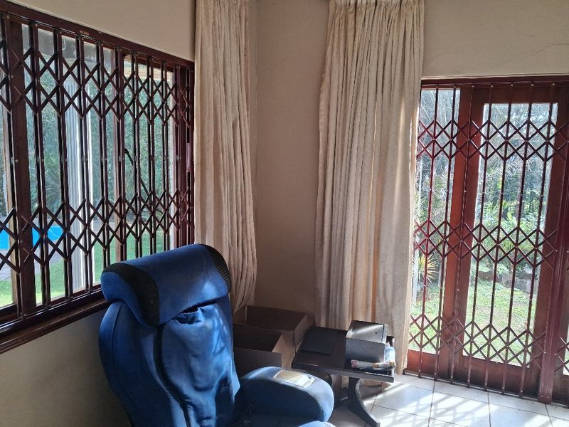 A living area featuring tiled flooring, security gates on windows and doors, and direct access to the garden.