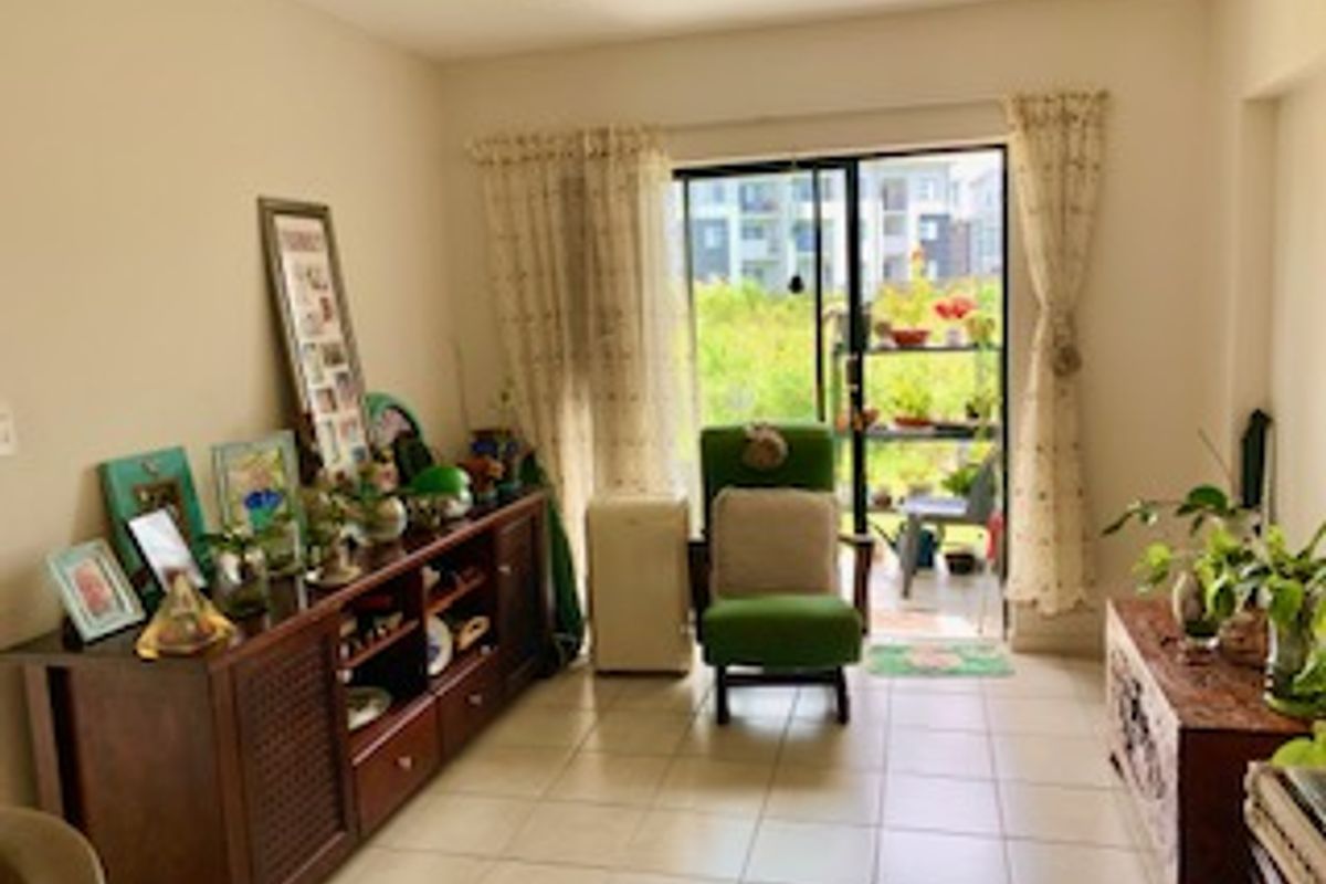 A living room featuring ceramic tile flooring and a sliding glass door providing access to an outdoor balcony area.