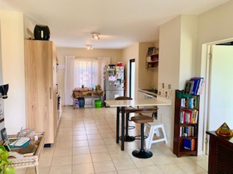 Open plan kitchen and living area featuring tiled flooring, built-in cabinetry, and a functional breakfast bar layout.