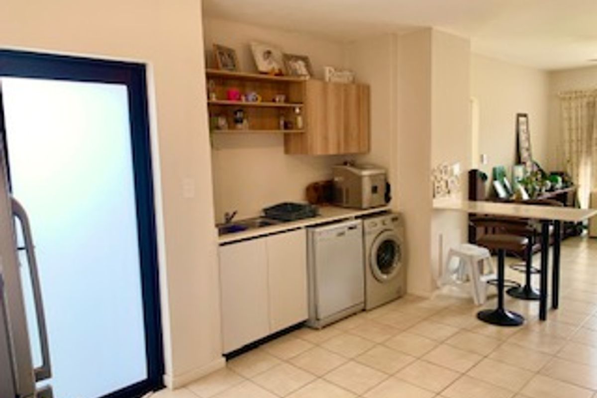 A functional kitchen area featuring built-in cabinetry, a sink, and tiled flooring, with an adjacent frosted glass door leading to the exterior.