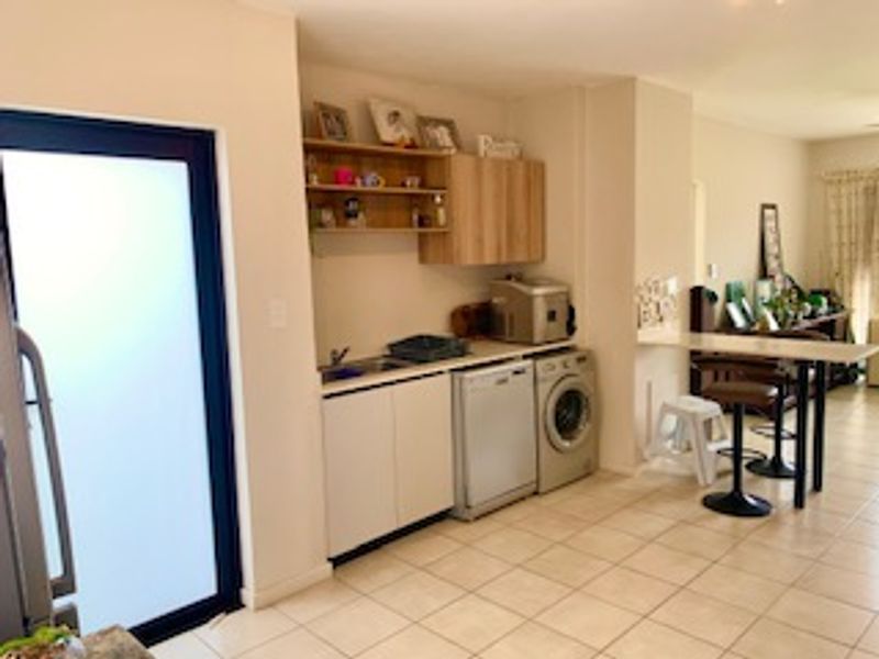 A functional kitchen area featuring built-in cabinetry, a sink, and tiled flooring, with an adjacent frosted glass door leading to the exterior.