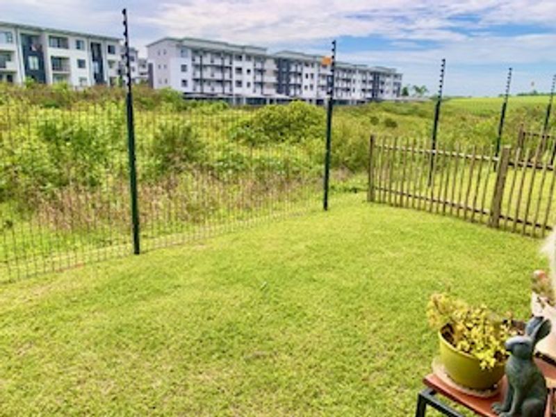 A private garden area featuring a well-maintained lawn, enclosed by a timber picket fence and secure electric perimeter fencing.