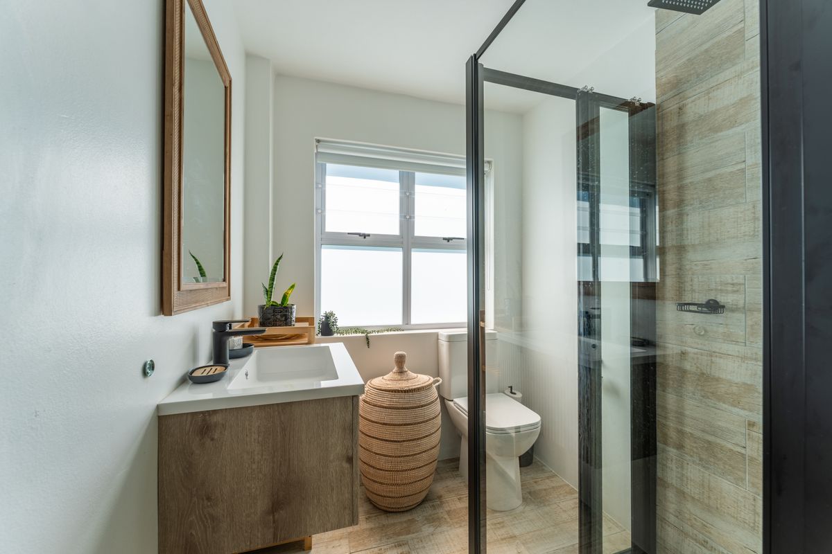Modern bathroom featuring a floating vanity, black tapware, a walk-in shower with wood-look tiling, and a clean, contemporary aesthetic.