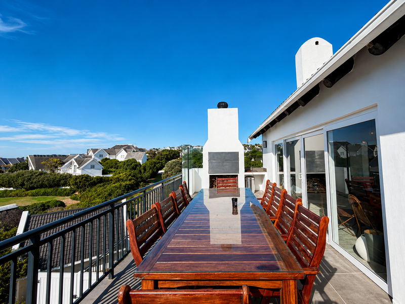 Spacious outdoor balcony featuring a built-in fireplace, tiled flooring, and glass balustrades, offering an ideal space for alfresco dining and entertaining.