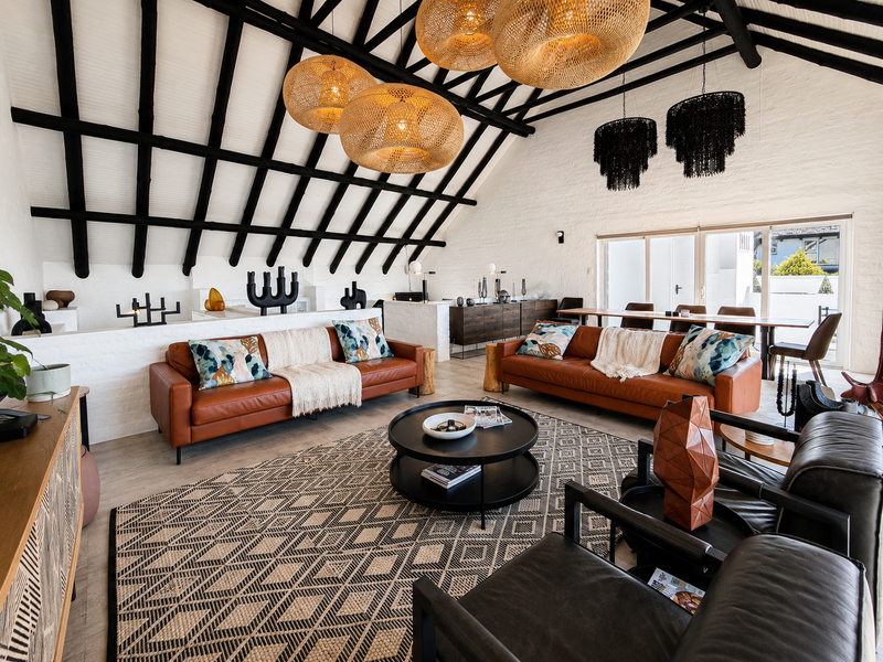 Spacious living area featuring a high vaulted ceiling with exposed timber rafters, painted brick walls, and large sliding glass doors leading to the exterior.