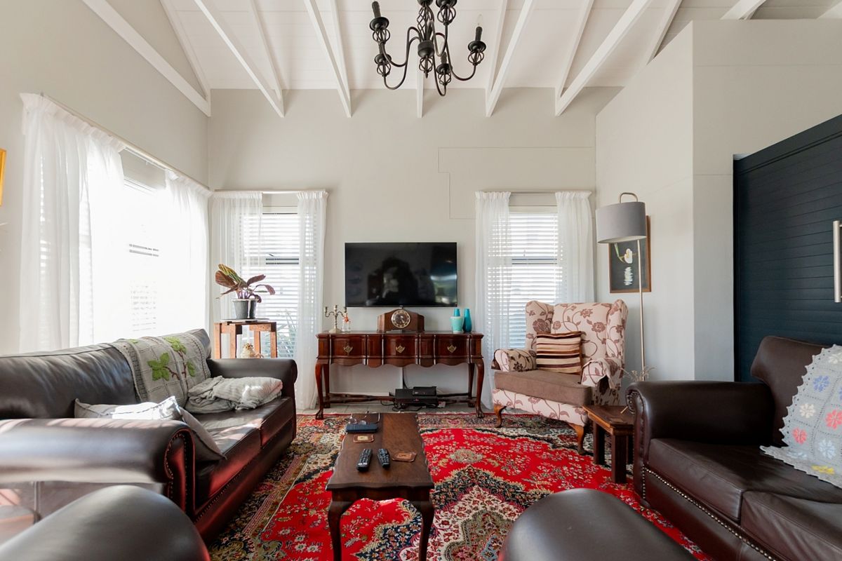 A bright living room featuring a high vaulted ceiling with exposed rafters and large windows, creating an airy and spacious atmosphere.