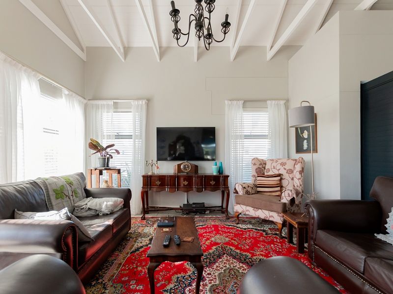 A bright living room featuring a high vaulted ceiling with exposed rafters and large windows, creating an airy and spacious atmosphere.