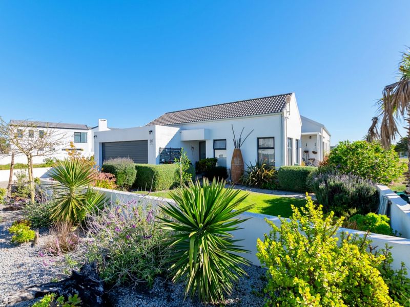 A well-maintained single-story house featuring a tiled roof, integrated garage, and a landscaped front garden with a low boundary wall.
