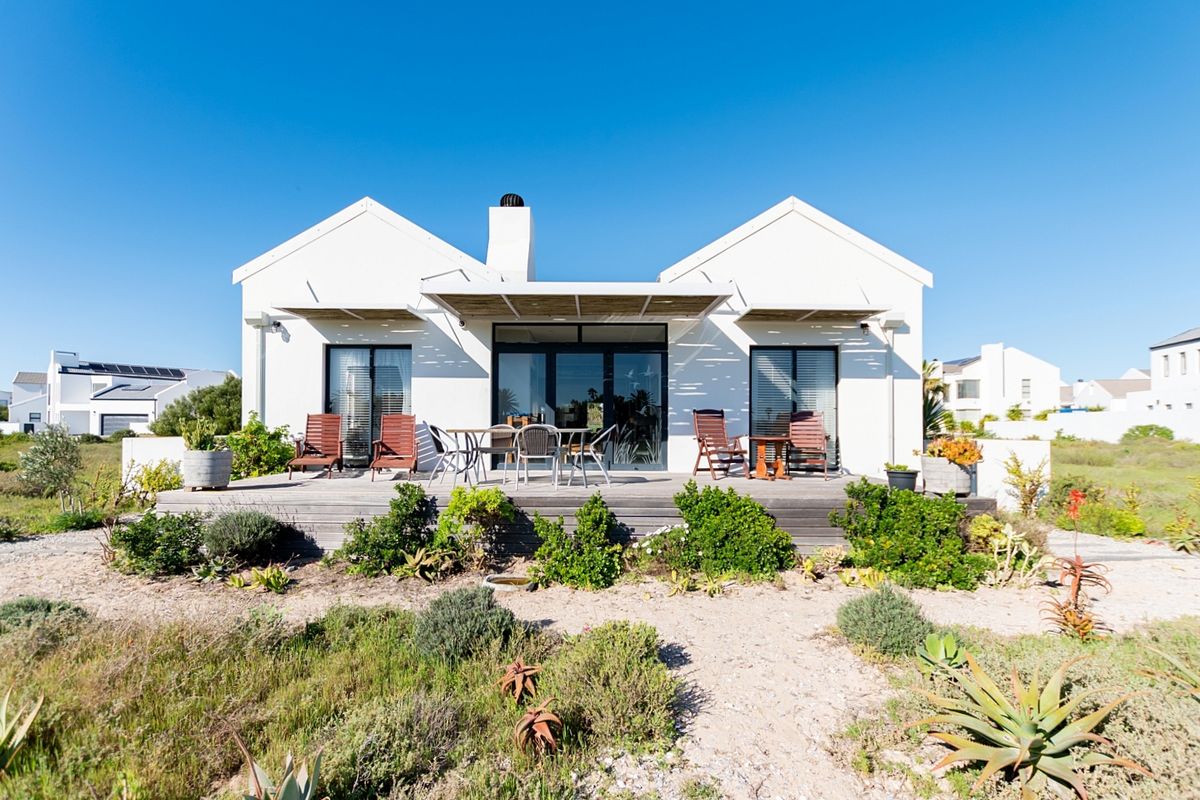 Rear view of a modern house featuring a timber deck, pergola, and sliding glass doors overlooking a landscaped garden.