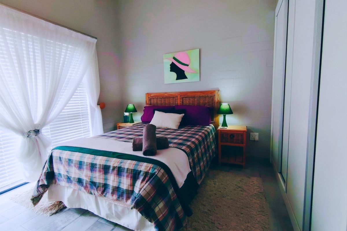 A well-lit bedroom featuring tiled flooring, a vaulted ceiling, and a built-in wardrobe with sliding doors, offering a comfortable and functional living space.