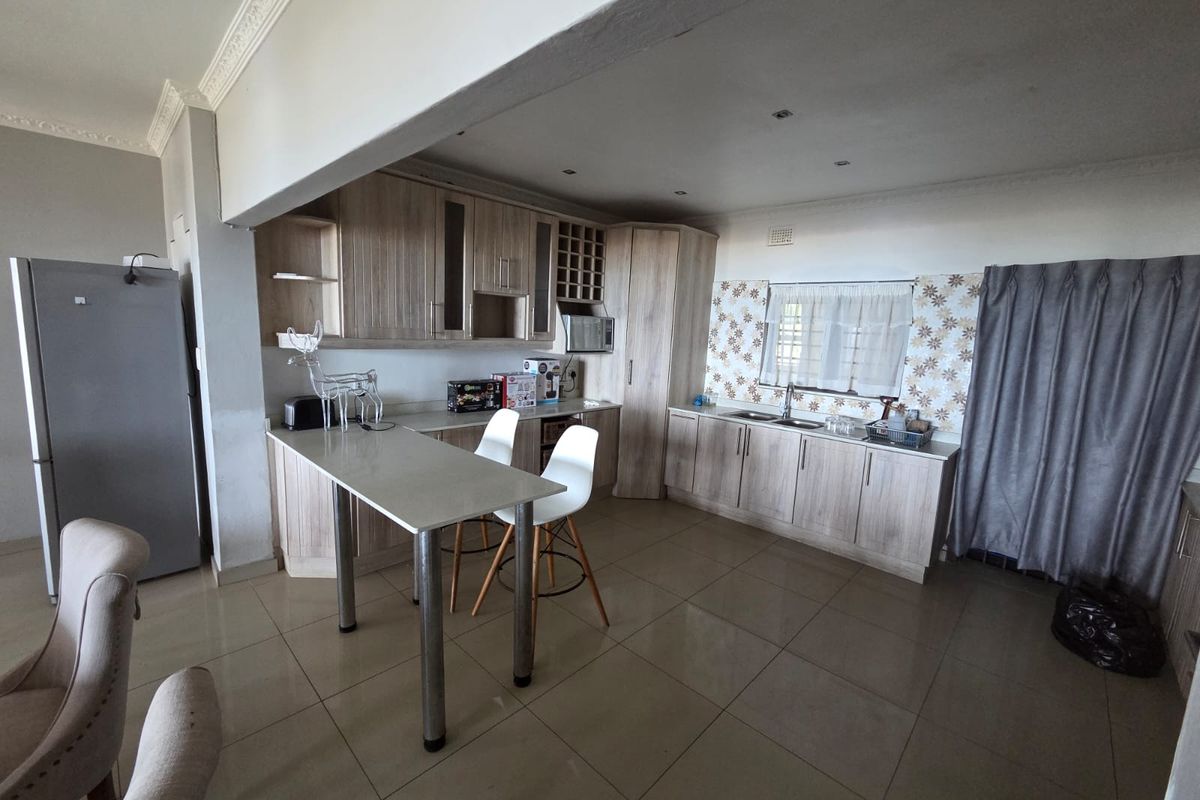 A functional kitchen featuring light wood-tone cabinetry, tiled flooring, a breakfast bar, and integrated storage, offering a practical layout for daily use.