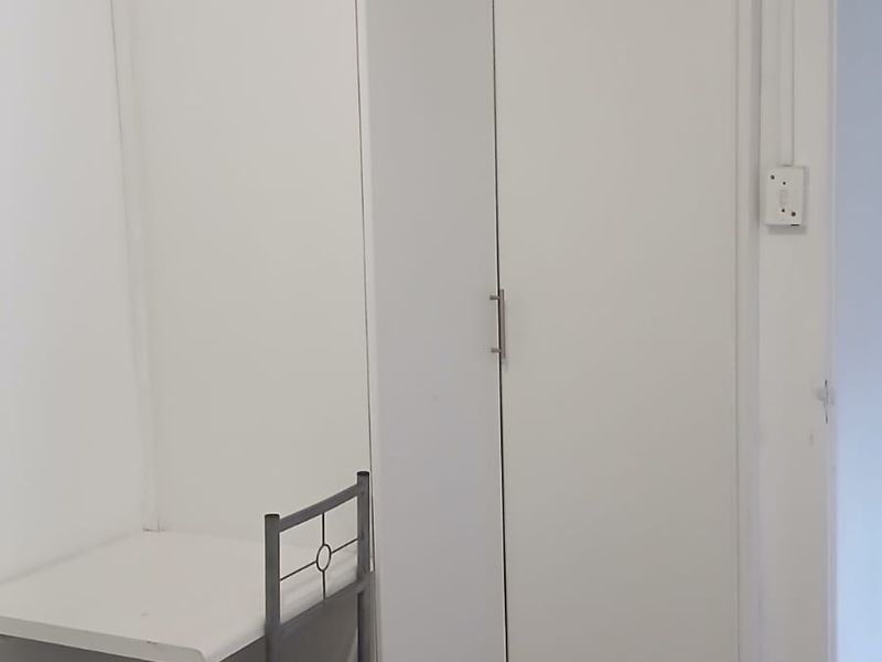 A bedroom featuring built-in white wardrobes and neutral tiled flooring, offering a clean and functional space.