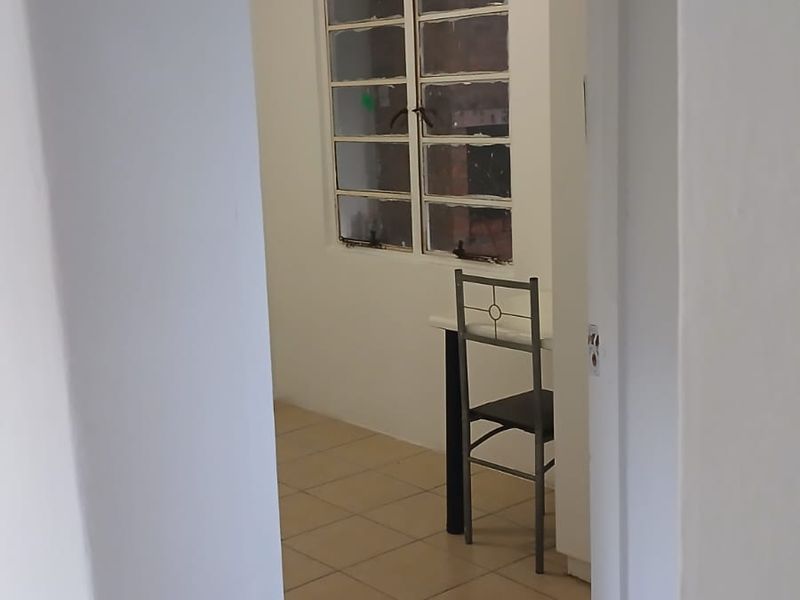 A compact kitchen area featuring tiled flooring and a multi-pane window, currently vacant and ready for renovation.