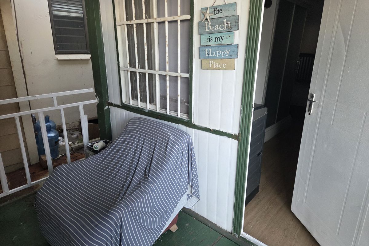 A small outdoor balcony area featuring security bars and direct access to the interior, showing signs of wear on the finishes.