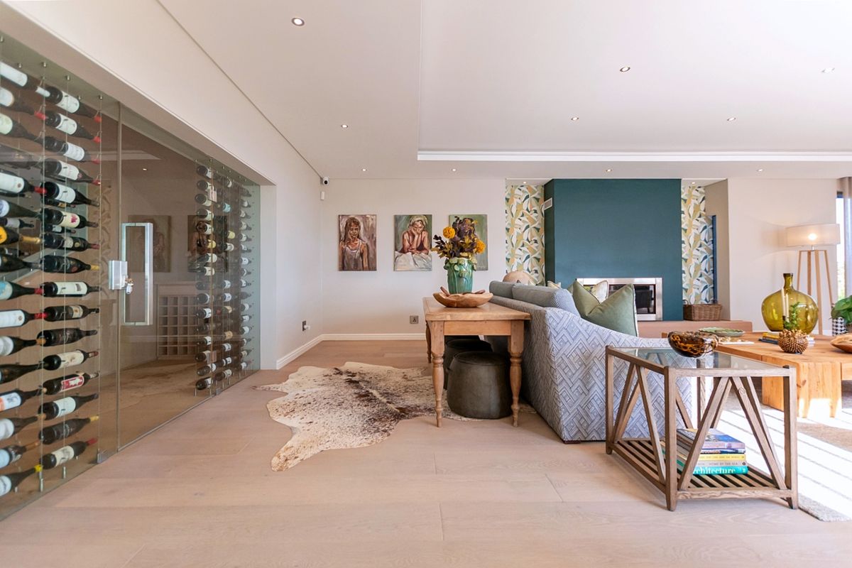 Spacious living area featuring a modern glass-enclosed wine cellar, built-in fireplace, and high-quality timber flooring with recessed lighting throughout.